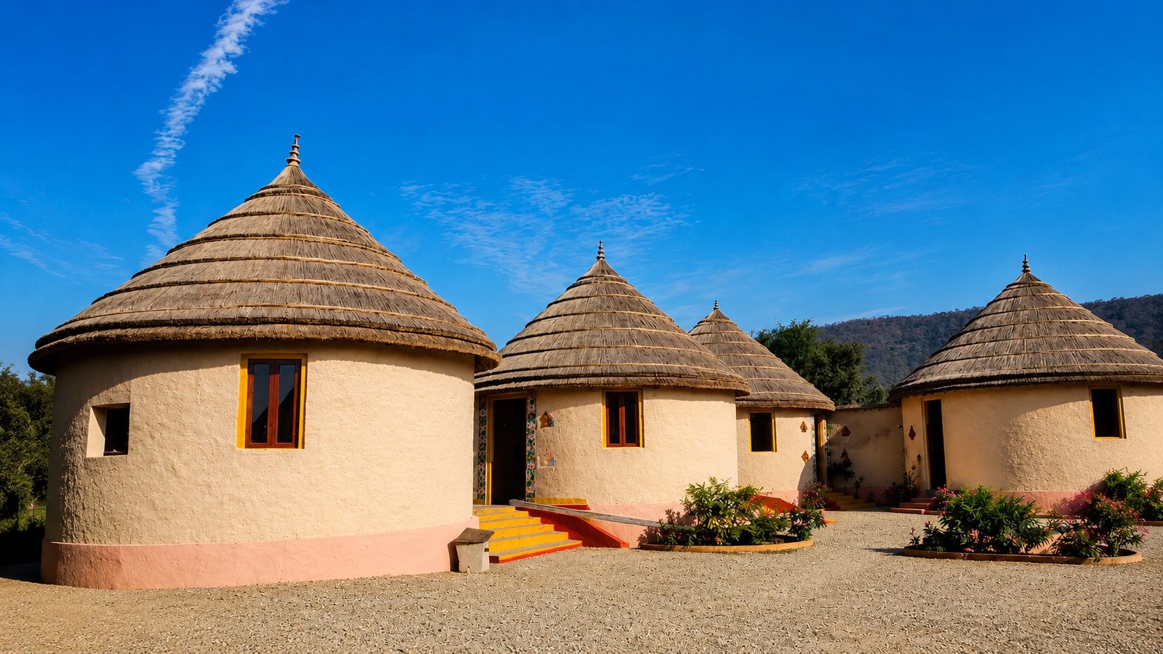 Cluster of thatched-dome mud cottages under a clear blue sky at Sariska Tiger Lodge