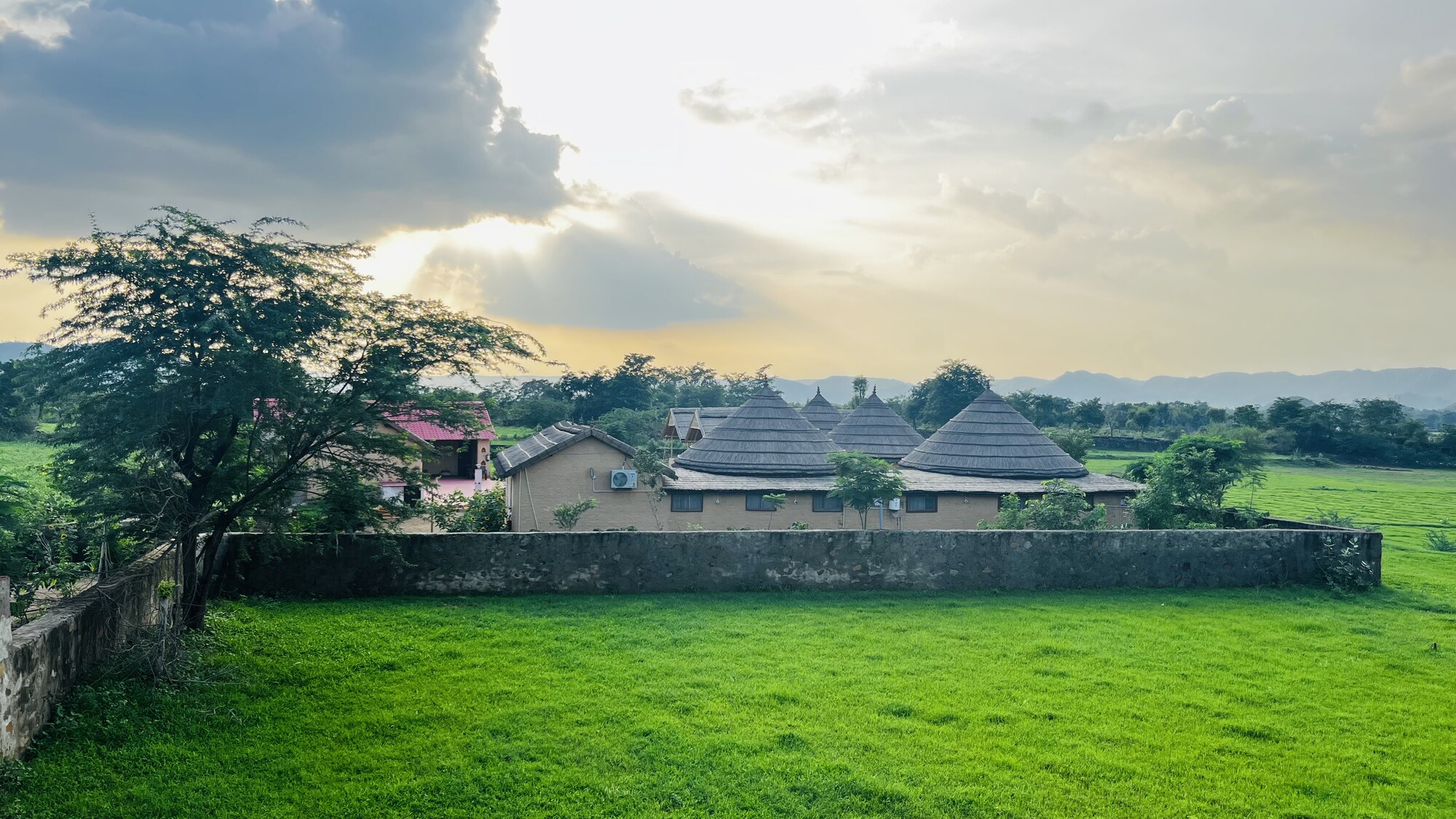 Mud cottage facade with landscaping at Sariska Tiger Lodge